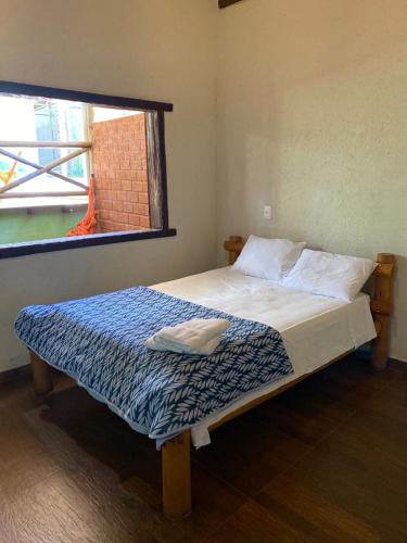 a bedroom with a bed with a blue and white blanket at Pousada Lapralapa in Santana do Riacho