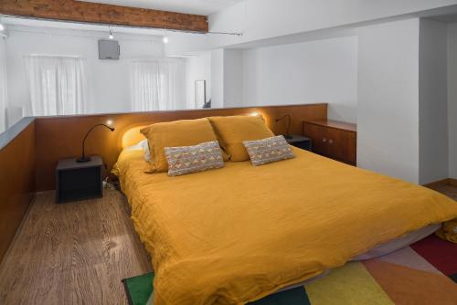 - une chambre avec un grand lit jaune et 2 oreillers dans l'établissement Le Loft Roquelaine, à Toulouse