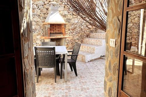 uma sala de jantar com mesa e cadeiras e uma parede de pedra em Casa La Fuente em Jabugo