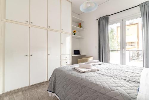 a white bedroom with a bed and a window at Evangeline City Center Apartment AC/WiFi in Heraklio