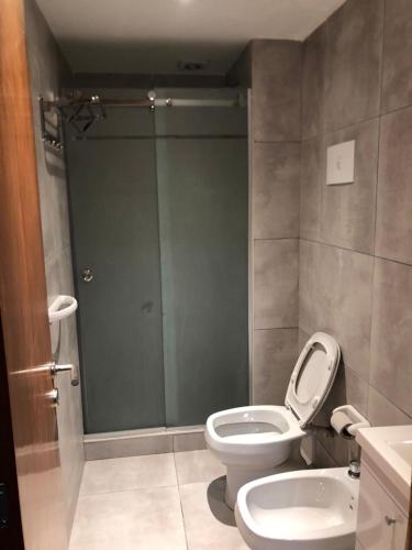 a bathroom with a toilet and a glass shower door at APARMENT Paraguay 341 in Rosario