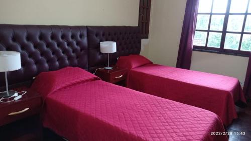 two beds in a hotel room with pink sheets at Hostería Familiar El Ceibo in San Salvador de Jujuy