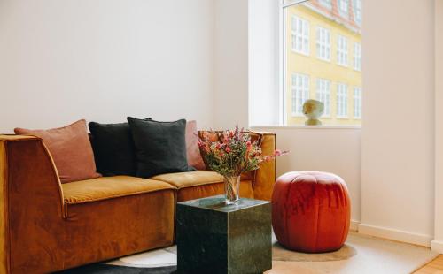 a living room with a couch and a vase of flowers on a table at Beautiful Apartments on Strøget in Copenhagen City Center in Copenhagen