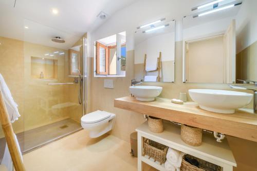 a bathroom with two sinks and a toilet and a shower at Menditzu Rooms in Biniaraix