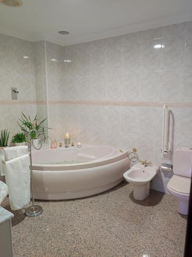a white bathroom with a tub and a toilet at Casa Rural Casa Valdecaballeros in Valdecaballeros