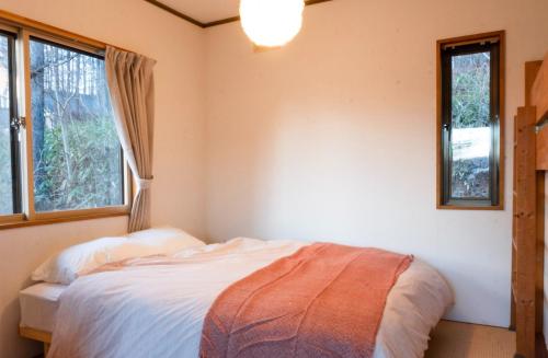 a bedroom with a bed and two windows at La Colina Retreat - Vacation STAY 07213v in Madarao Kogen