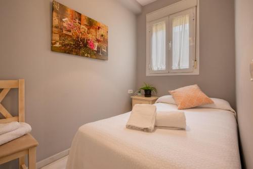 um quarto com uma cama branca e uma janela em Precioso apartamento en Triana em Sevilha