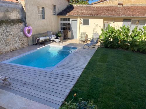 une cour arrière avec une piscine et une terrasse en bois dans l'établissement AU PLAISIR D ETAPE- ACCUEIL PELERINS uniquement, à Condom