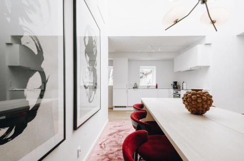 a white kitchen with a table and red chairs at Beautiful Apartments on Strøget in Copenhagen City Center in Copenhagen