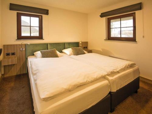 a large white bed in a room with two windows at Holiday Resort Van der Valk, Linstow in Linstow