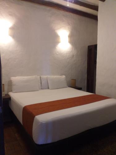 a bedroom with a bed with two lights on the wall at Casona CHARA in Barichara