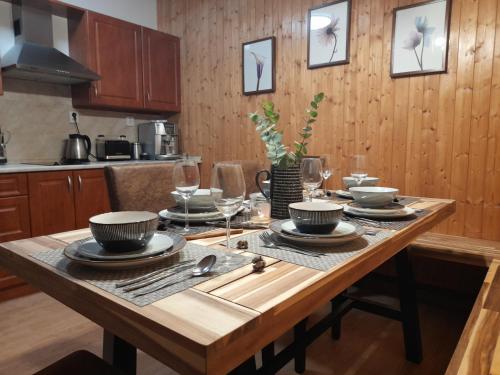 a wooden table with plates and glasses on it in a kitchen at Apartmá Ráj v Ramzové in Ostružná