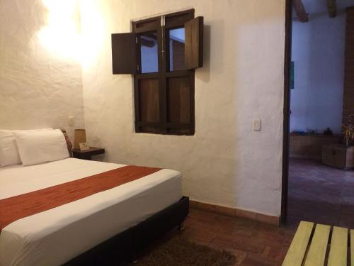 a bedroom with a bed and a window and a door at Casona CHARA in Barichara