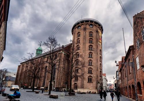 a large brick building with a clock tower on a street at Beautiful Apartments on Strøget in Copenhagen City Center in Copenhagen