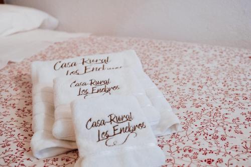 two white towels sitting on top of a bed at Casa Rural los Enebros in Los Navalucillos