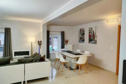a living room with a couch and a table and chairs at Modern 3 bedroom apartment near Useldange castle in Useldange