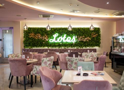 a restaurant with tables and chairs and a neon sign at Garni Hotel Lotos in Niš