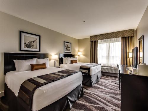 a hotel room with two beds and a television at Radisson Hotel Edmonton Airport in Leduc