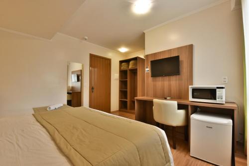 Habitación de hotel con cama y escritorio con microondas en Pousada Stillo Gramado en Gramado