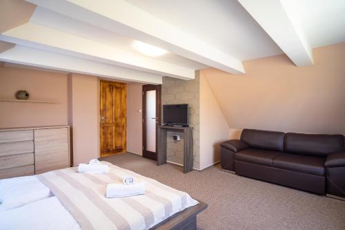 um quarto de hotel com uma cama e um sofá em Lator-Boross Vendégház em Villány