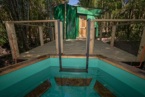 una casa con una piscina de agua y un puente de madera en Cabañas Ensenada Bosque Nativo, en La Ensenada