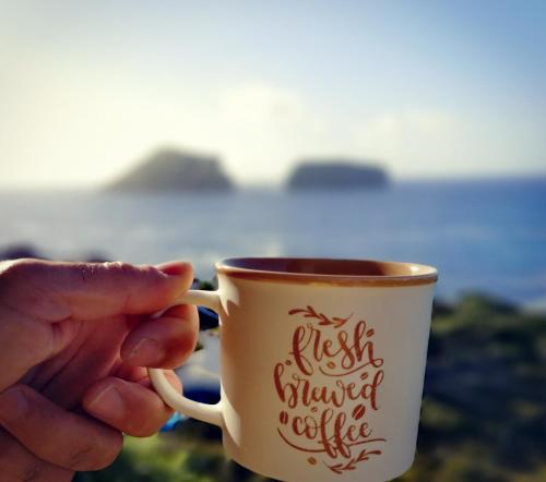 a person holding a coffee cup with the words risk shared coffee at Breathe Nature - Beach House Azores in Feteira