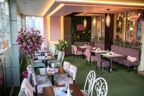 a restaurant with tables and chairs and flowers at Garni Hotel Lotos in Niš