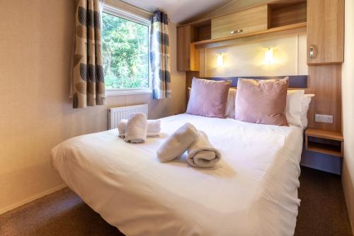 a bedroom with a white bed with towels on it at Beechcroft - Norfolk Cottage Agency in Holt
