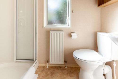 a bathroom with a toilet and a window at Beechcroft - Norfolk Cottage Agency in Holt