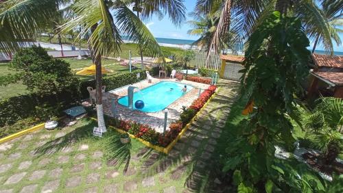 uma vista sobre uma piscina com palmeiras e o oceano em POUSADA CANEDO em Guaibim