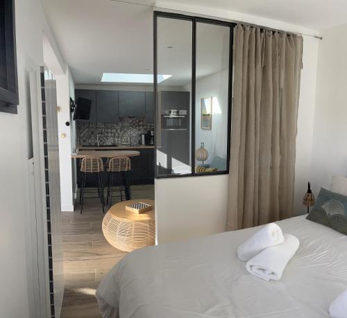 a bedroom with a white bed and a kitchen at Lodge LE CABANON accès direct plage ! in La Turballe