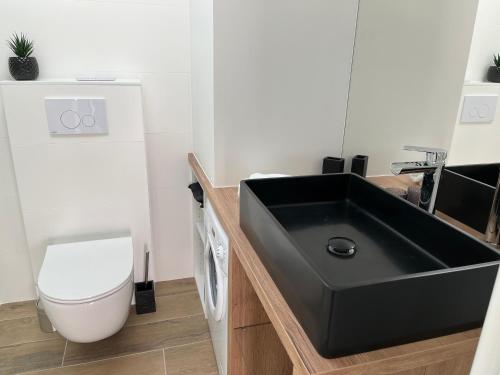 a bathroom with a black sink and a toilet at Lodge LE CABANON accès direct plage ! in La Turballe