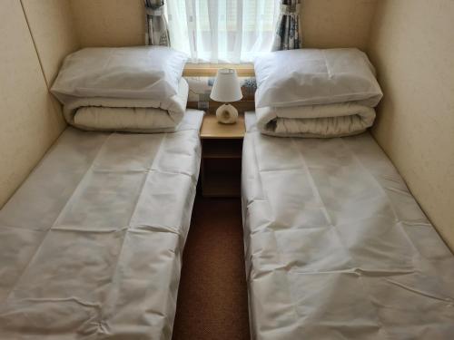 two twin beds in a small room with a table at 6 Berth Promenade Ingoldmells (Ruby) in Ingoldmells