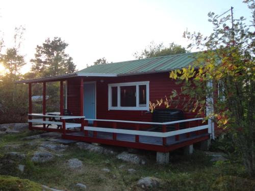 une petite maison rouge avec une grande terrasse dans l'établissement Sommarö Stugor, à Föglö