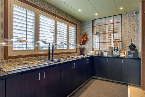 a kitchen with dark wood cabinets and windows at Best Western Plus Brookside Inn in Milpitas