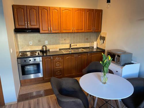 uma cozinha com armários de madeira e uma mesa e cadeiras brancas em Apartmán Pošta em Rajecké Teplice