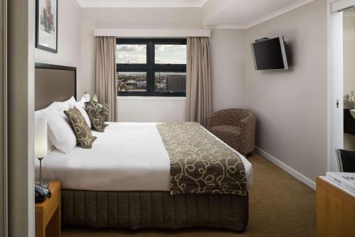 a hotel room with a bed and a window at Rydges Mackay Suites in Mackay