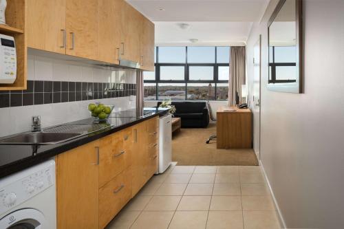 a kitchen with a sink and a dishwasher at Rydges Mackay Suites in Mackay