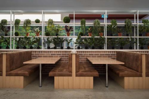 a restaurant with benches and tables and potted plants at Rydges Mackay Suites in Mackay