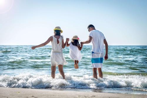 three people standing in the water at the beach at Saint Kilda Beach Hotel - formerly Rydges St Kilda in Melbourne