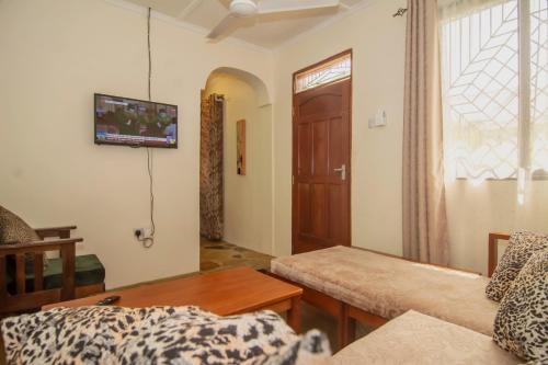 ein Wohnzimmer mit einem Sofa und einem TV an der Wand in der Unterkunft Amarrosi Buffalo-One Bedroom apartment, Mtwapa in Mtwapa