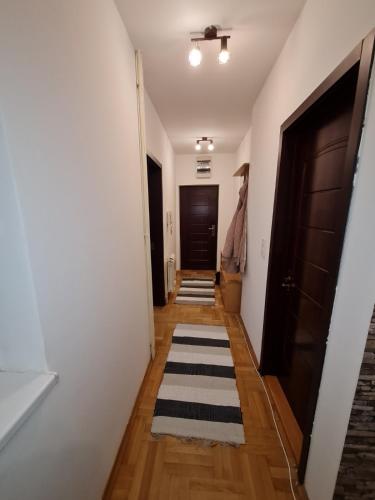 a hallway with a door and a rug on the floor at Lux Apartment Rose 2 60m2 in Kragujevac