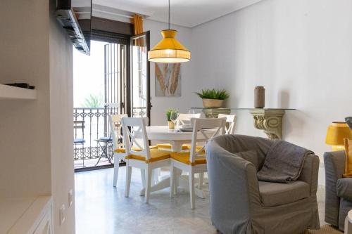 Precioso apartamento en el casco histórico في إشبيلية: غرفة طعام وغرفة معيشة مع طاولة وكراسي