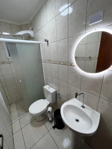 La salle de bains est pourvue de toilettes, d'un lavabo et d'un miroir. dans l'établissement Apto Luxo Praia Grande 50m da Praia WI-FI Familiar, à Praia Grande