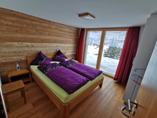 een slaapkamer met een bed met paarse lakens en een raam bij Chalet Enzian in Riederalp