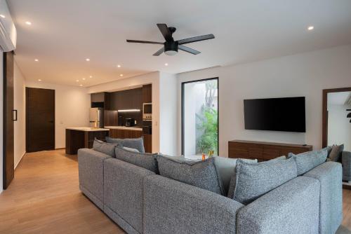 a living room with a couch and a flat screen tv at Suites at TreeTops Tulum in Tulum