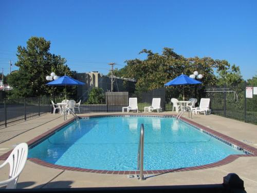 una piscina con sillas blancas y sombrillas azules en Express Inn Eureka Springs en Eureka Springs