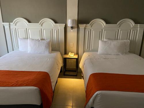 a hotel room with two beds and a telephone at HOTEL LOS ROBLES in Nuevo Laredo