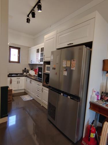 eine Küche mit einem Kühlschrank aus Edelstahl und weißen Schränken in der Unterkunft The Castle Stay in Chuncheon
