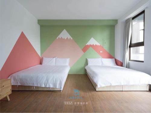 1 dormitorio con 2 camas con montañas pintadas en la pared en Muco Muco Bnb, en Yilan City